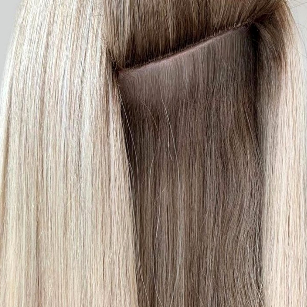 Närbild på ett platt invisible weft-fäste i blont hår